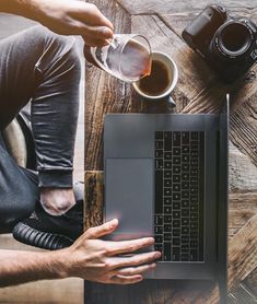 a person sitting at a table with a laptop and cup of coffee in front of them