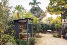 a small black shed sitting in the middle of a forest