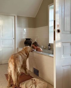 a golden retriever dog standing at the edge of a bathtub with his owner