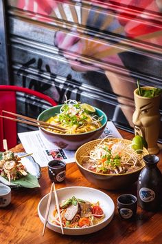 two bowls of food sit on a table with chopsticks in front of them