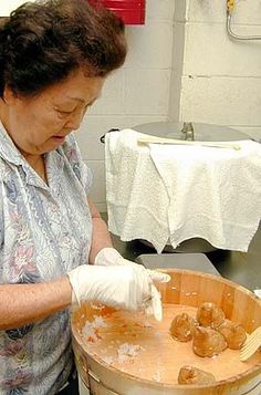 an older woman is making food in a bucket