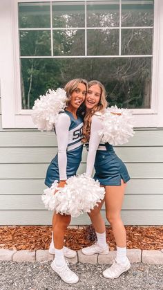 two cheerleaders posing for the camera in front of a house