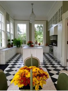 a kitchen with black and white checkered flooring has flowers on the dining room table