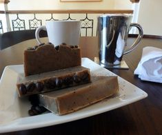 two pieces of soap sitting on top of a white plate next to a coffee cup