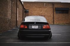 a black car parked in a parking lot next to a brick building