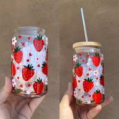 two hand painted mason jars with strawberries and flowers on them, one is holding a straw