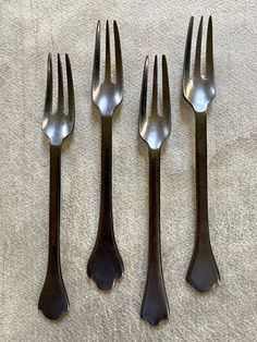 four forks and two spoons sitting next to each other on top of a table