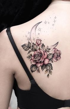 a woman's back with roses and a crescent tattoo