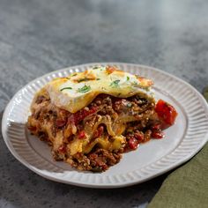 a white plate topped with lasagna covered in meat and cheese on top of a table