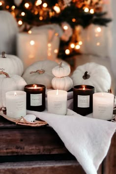 some candles are sitting on a table with white pumpkins and other decorations in the background