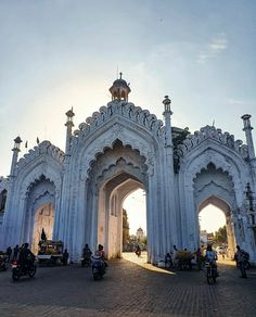 people are riding motorcycles in front of an ornate white building with arches and doorways