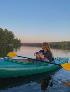 a woman sitting in a green kayak on the water