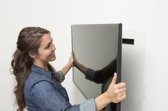 a woman holding onto the back of a black wall mounted display unit with her hands on it