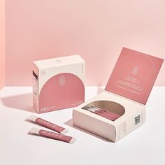 the packaging is pink and white, with three tubes in front of it on a table