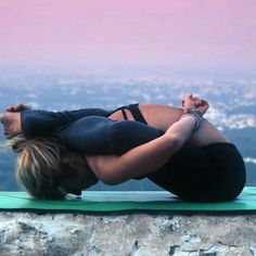 a woman doing yoga on top of a mountain