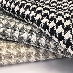 three different colored knitted fabrics stacked on top of each other, one black and white