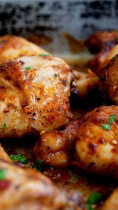 some chicken is cooking in a pan with parsley on the top and green garnish on the bottom