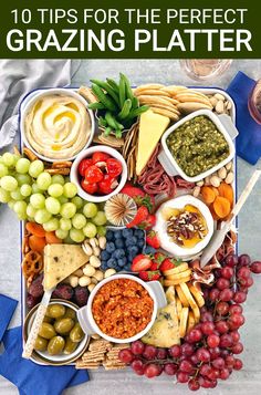 a tray filled with cheese, crackers and other foods next to a glass of wine