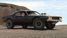 a black muscle car parked in the desert