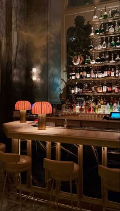 a dimly lit bar with several stools and bottles on the wall behind it,