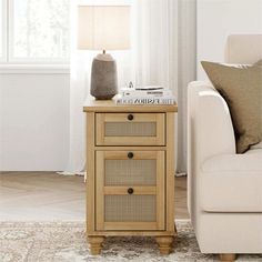 a white couch sitting next to a table with two drawers on it and a lamp