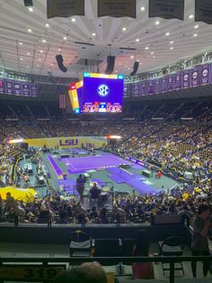 a large crowd is watching a tennis match in a big stadium with purple and yellow colors