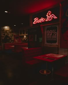 the interior of a restaurant with red neon signs on the wall and booths in the background