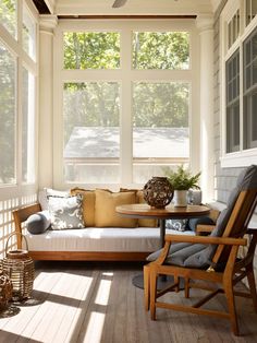 the sun shines through the large windows in this porch with white walls and wood flooring