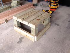 a table made out of wooden pallets and some tools on the ground next to it