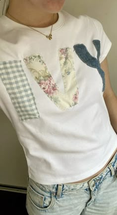 a woman wearing a white t - shirt with floral appliques on it's chest