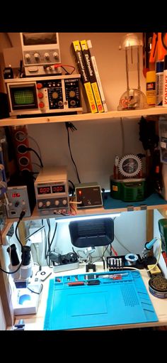 a computer desk with various electronics on top of it and bookshelves in the background