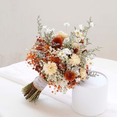 a bouquet of flowers sitting on top of a white table next to a canister