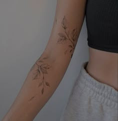 a woman's arm with leaves on it and a tattoo design on the wrist