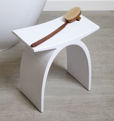 a wooden brush sits on top of a white stand in front of a bathtub