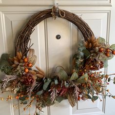 a wreath is hanging on the front door with berries, leaves and acorns