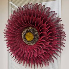 a large red sunflower hanging on the side of a white door with shutters