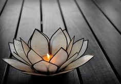 a candle that is sitting on a wooden table with a flower shaped light in the middle