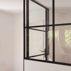 an empty room with white walls and black glass window frames on the wall, in front of a computer desk