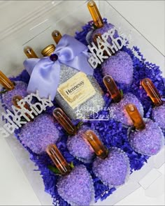 purple flowers and candles are arranged in a clear box