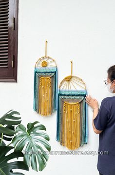 a woman standing next to two wall hangings with gold and blue decorations on them