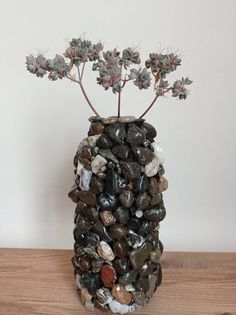 a vase filled with rocks and plants on top of a wooden table