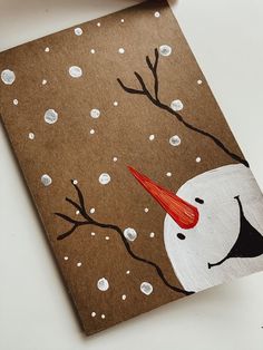 a brown card with a white snowman and red hat on it's head