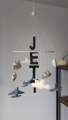 a mobile with birds and letters hanging from it's sides in the shape of clouds