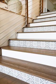 some stairs with white and brown tile on the bottom, and wood handrails