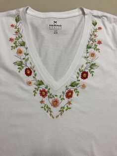 a white shirt with flowers and leaves on it