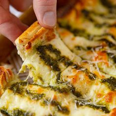 a person taking a slice of pizza with cheese and spinach