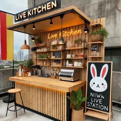 an outdoor food stand with wooden shelves and signs on the wall, along with two stools