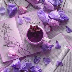 an open book with purple flowers on it and a cup of tea next to it