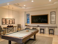 a pool table and chairs in a room with a chalkboard on the wall behind it