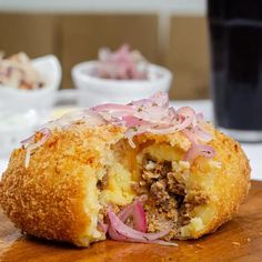 a close up of food on a cutting board with a drink in the background at a restaurant